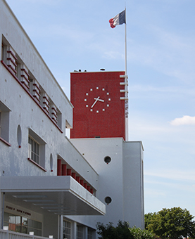 Cadran sur un immeuble rouge brique avec un drapeau Français